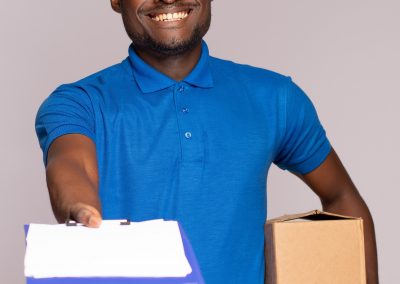 Handsome,Black,Delivery,Worker,Holding,A,Package,And,Handing,Forward